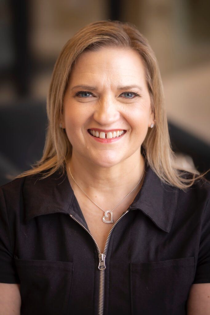 Michon Henegar smiles in a black top, representing authentic leadership, strategic focus, and professional empowerment.